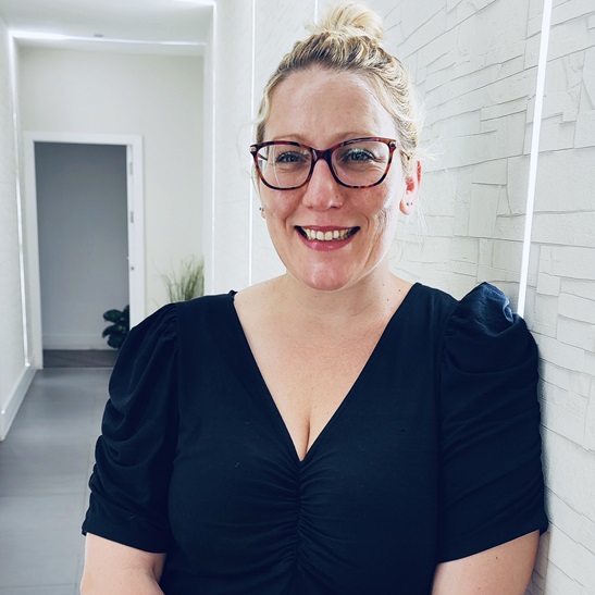 Hypnotherapist Emma Roberts earing a black top and black framed glasses